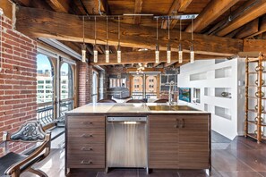 A modern kitchen with a large island, wooden beams, and hanging pendant lights. - Spacious & Charming 3BR - Heart of Old Montreal (Montréal)