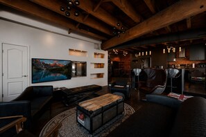 A modern living room with a large painting, a piano, and a rustic wooden ceiling. - Spacious & Charming 3BR - Heart of Old Montreal (Montréal)