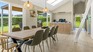 A modern kitchen with a large island, a dining area with a wooden table and chairs, and a view of the outdoors. - "Illona" - 200m from the sea by Interhome (Hejls)