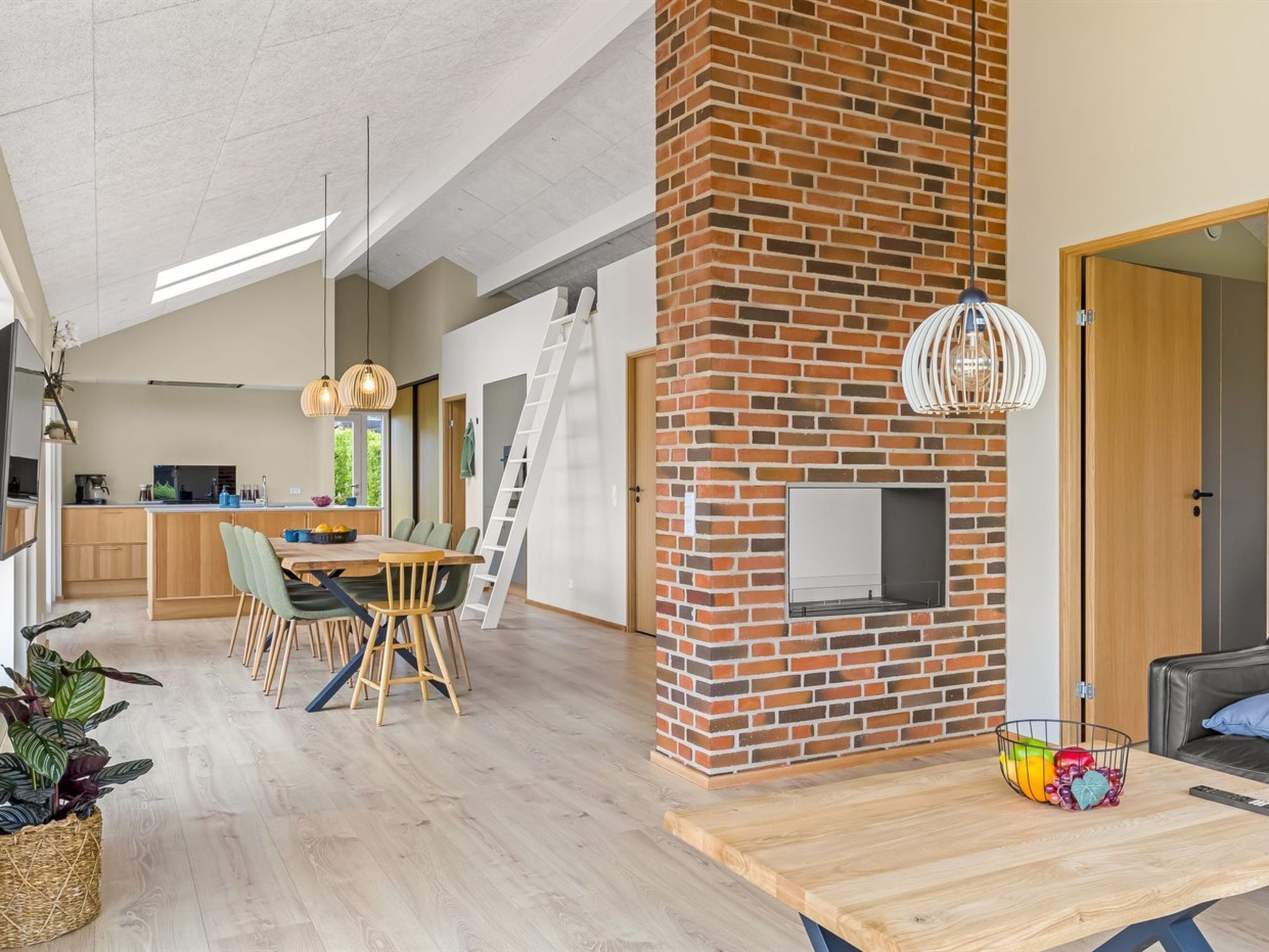 Una cocina moderna con una pared de ladrillo decorativa, un área de comedor con mobiliario de madera y una isla visible.