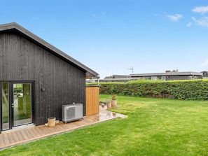Un bâtiment moderne à l’extérieur sombre, doté d’une porte d’entrée en verre et d’un petit espace extérieur avec une terrasse en bois et un grand appareil.