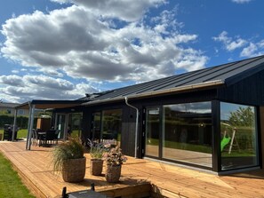 Ein modernes Haus mit einer Terrasse, großen Fenstern und blauem Himmel.