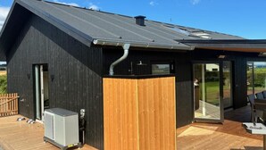 A modern building with a dark exterior, a wooden deck, and a glass door leading to an outdoor area. - "Illona" - 200m from the sea by Interhome (Hejls)
