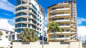 A modern multi-story building with a prominent 'WYUNA' sign, featuring balconies and a flat roof design. - Wyuna Ocean Views in Burleigh (Gold Coast)
