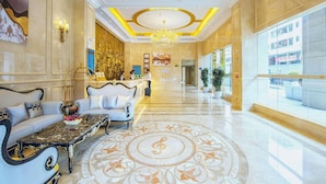 A hotel lobby with a reception desk, seating area, and a chandelier.