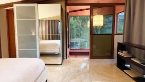 Ein Schlafzimmer mit Bett, Kleiderschrank, Fernseher und einer Schiebetür, die auf einen Balkon führt.