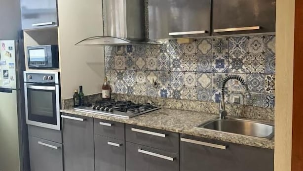 A modern kitchen with stainless steel appliances, a tiled backsplash, and a built-in oven.