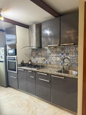 Une cuisine moderne dotée d’appareils électroménagers en acier inoxydable, d’un revêtement mural en carreaux et d’un four encastré.