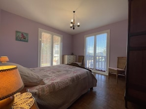 Ein Schlafzimmer mit einem Bett, einem Nachttisch, einer Kommode und einem Sessel.