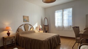 A bedroom with a bed, bedside tables, a chair, a mirror, and a window with curtains. - MENDIKO-LOREA - SAINT-PEE-SUR-NIVELLE (SAINT-PEE-SUR-NIVELLE)