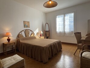 A bedroom with a bed, bedside tables, a chair, a mirror, and a window with curtains. - MENDIKO-LOREA - SAINT-PEE-SUR-NIVELLE (SAINT-PEE-SUR-NIVELLE)