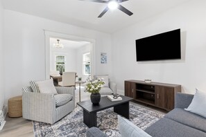 Ein Wohnzimmer mit gestreiften Sofas, einem Couchtisch, einem Flachbildfernseher und einem Holzschrank.