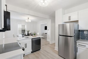A modern kitchen with stainless steel appliances, white cabinetry, and a central island.