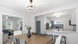 A modern kitchen with a central island, white cabinetry, and a chandelier. - Historic 4BR Home Near South Wedge & Park Ave - Family Friendly with A/C (Rochester)