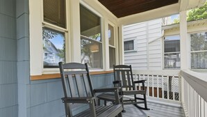 A covered porch with two rocking chairs and a view of neighboring houses. - Historic 4BR Home Near South Wedge & Park Ave - Family Friendly with A/C (Rochester)