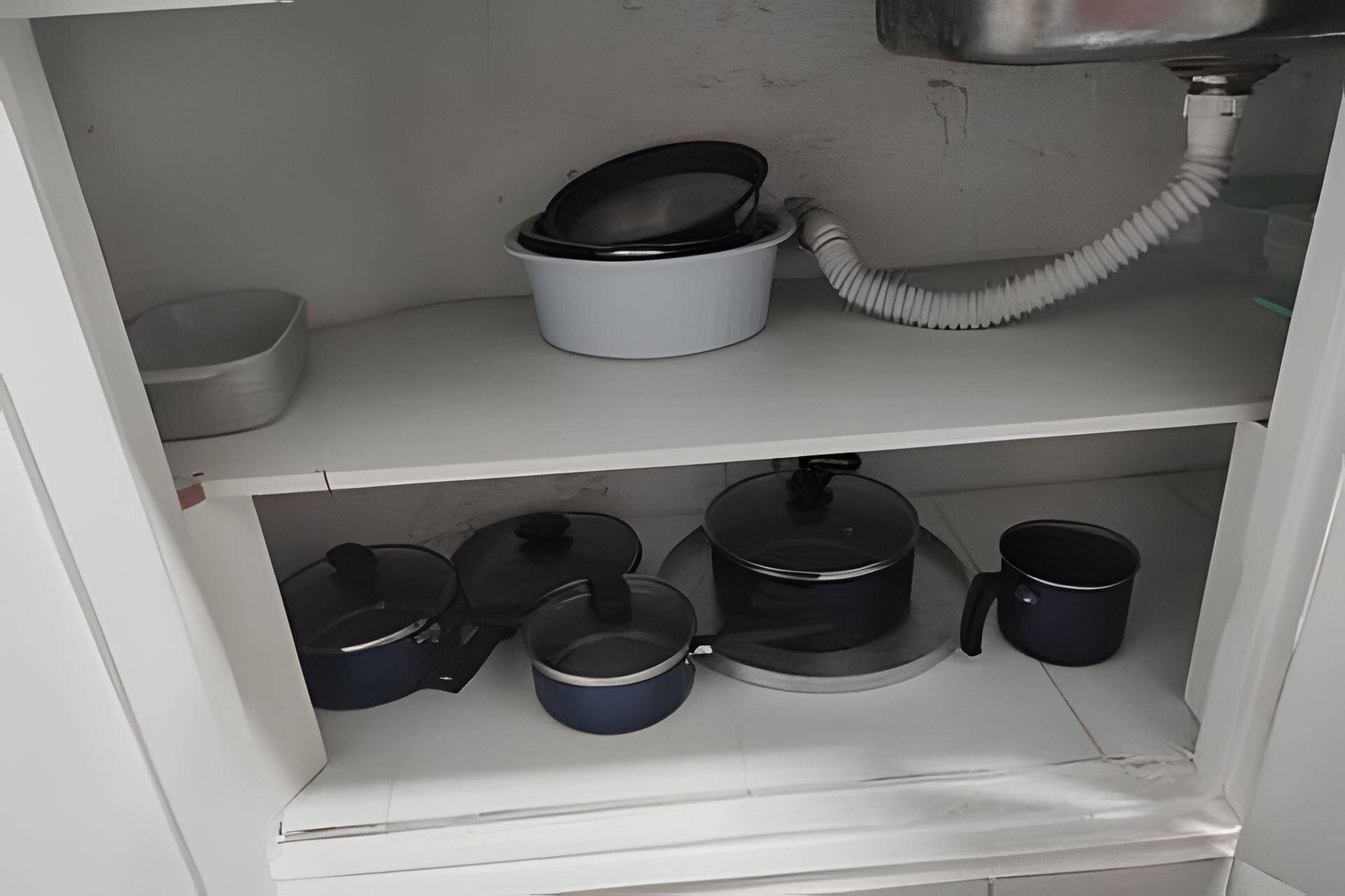 A kitchen cabinet with pots and pans.