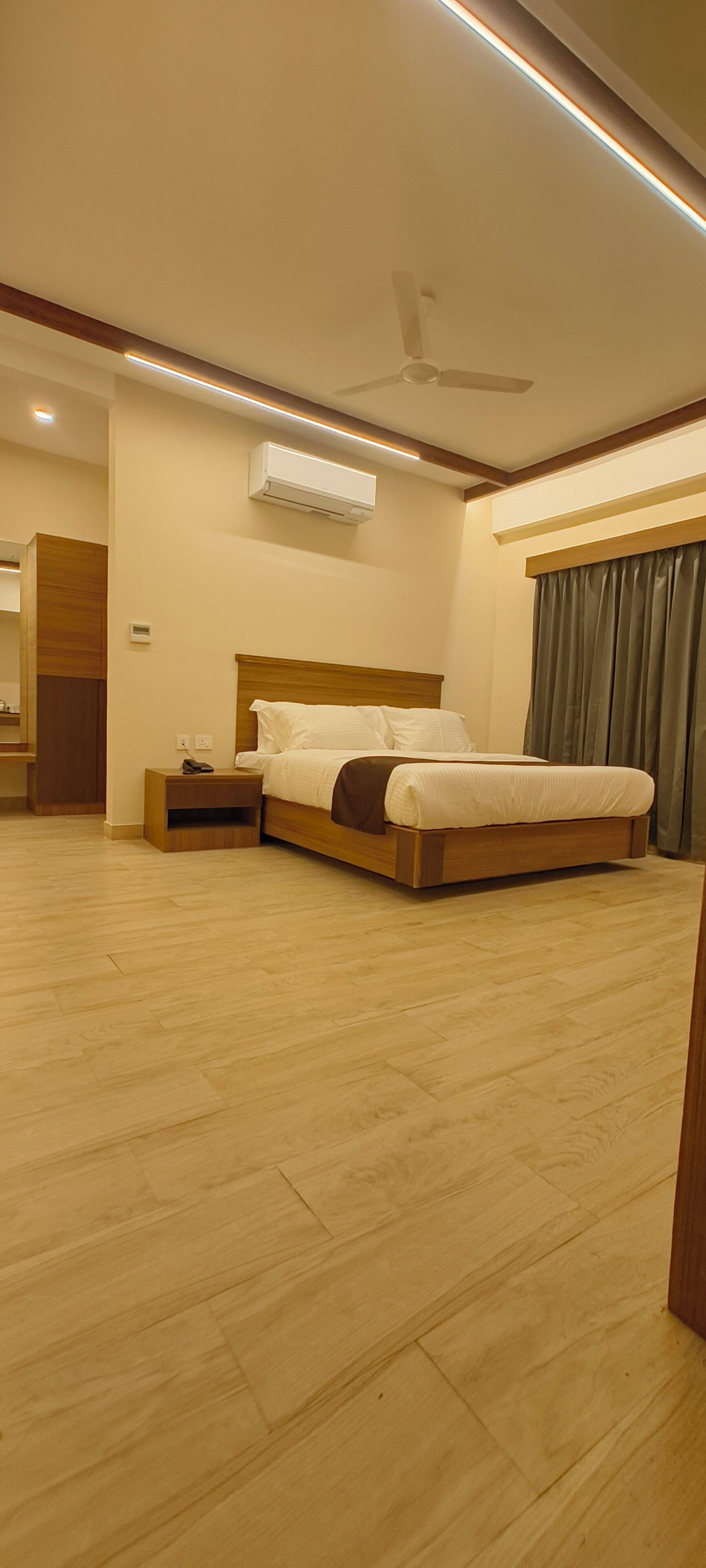 A hotel room with a bed, bedside table, and an air conditioning unit.