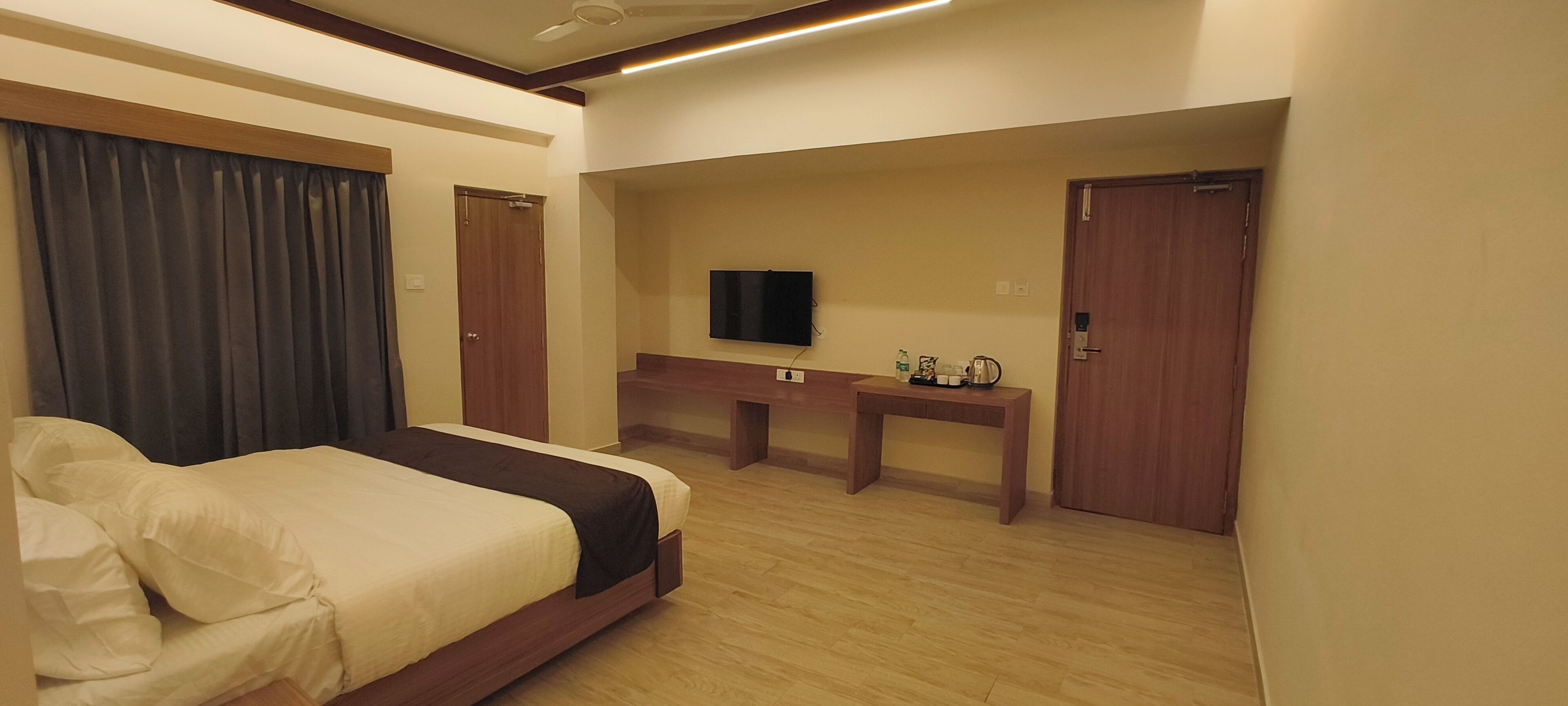 A hotel room with a bed, a desk, a television, and a door.