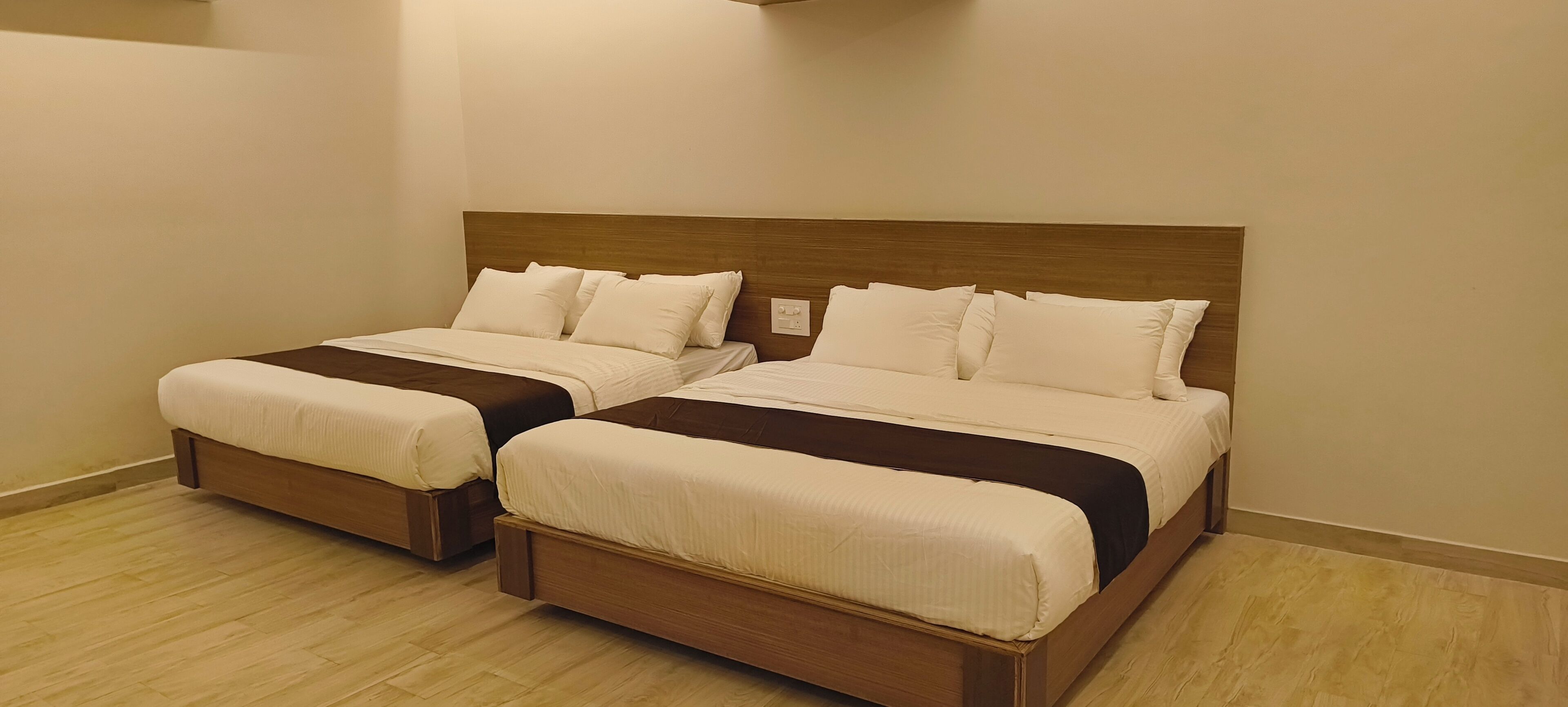 Habitación de hotel con dos camas individuales, cabeceros de madera y suelo de color claro.