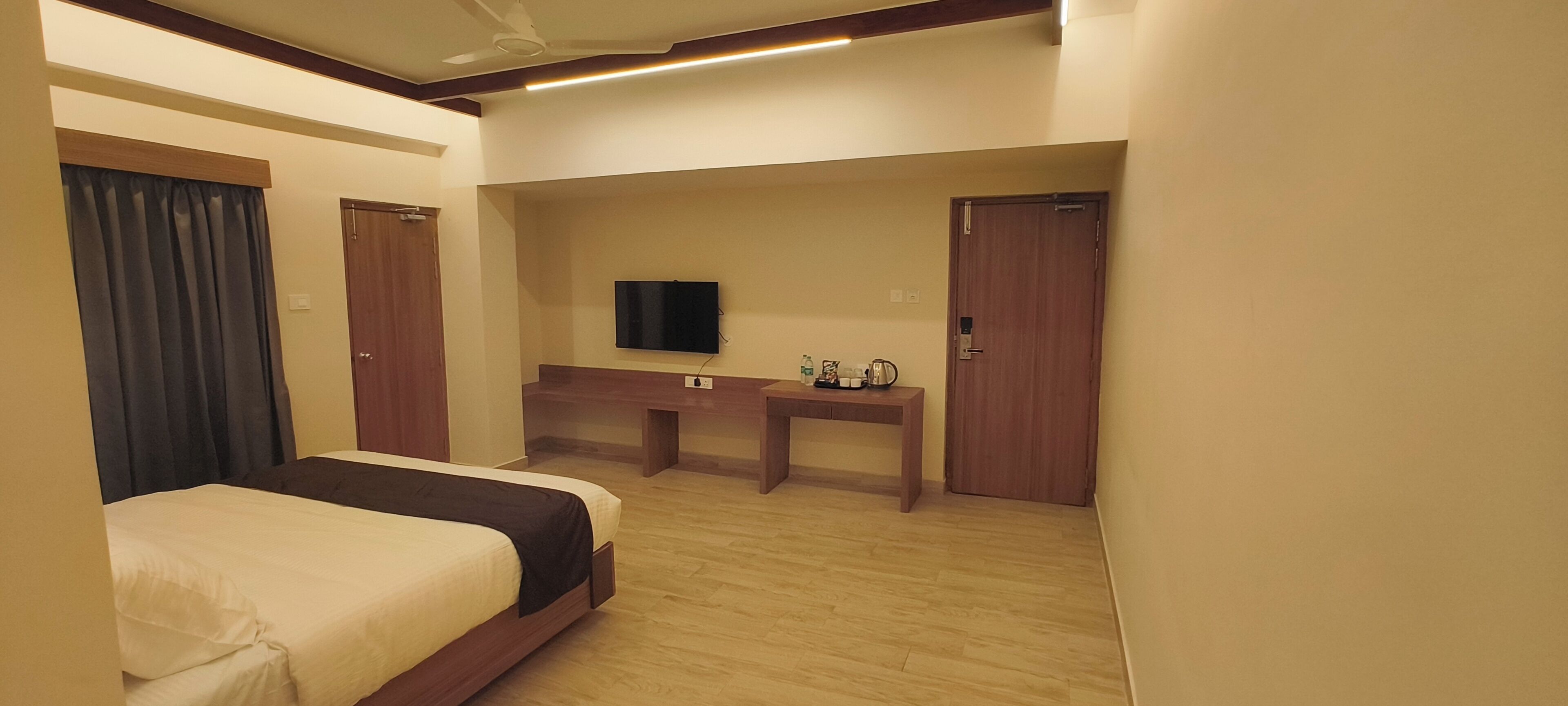 Une chambre d’hôtel avec un lit, un bureau, une télévision et une porte.