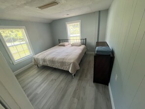 A bedroom with a bed, two windows, a dresser, and a ceiling vent. - Adorable 2-bedroom house with AC in charming Lusby (Lusby)