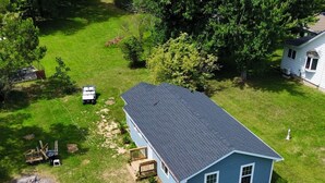A residential property with a large house, a smaller attached structure, a boat, and a paved driveway. - Adorable 2-bedroom house with AC in charming Lusby (Lusby)