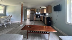 A modern kitchen with stainless steel appliances, wooden cabinets, and a flat-screen TV mounted on the wall. - Adorable 2-bedroom house with AC in charming Lusby (Lusby)