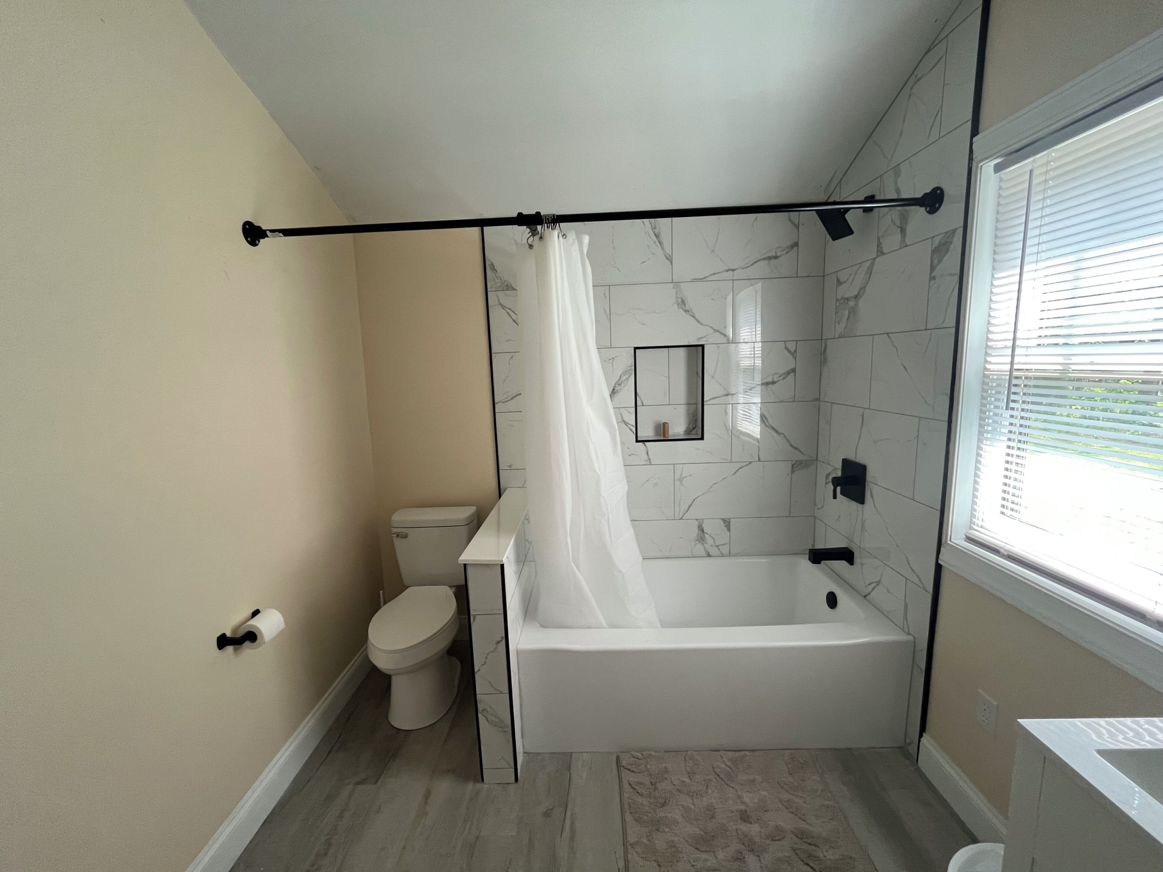 Et badeværelse med toilet, badekar og brusenik.