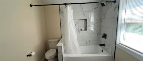Une salle de bain équipée de toilettes, d’une baignoire et d’un rideau de douche.