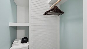 A bathroom with a white towel rack, a shelf with folded towels, and a makeup bag. - Ruby's Coop (Bryson City)
