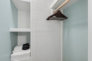 Ein Badezimmer mit weißem Handtuchhalter, einer Ablage mit gefalteten Handtüchern und einer Kosmetiktasche.