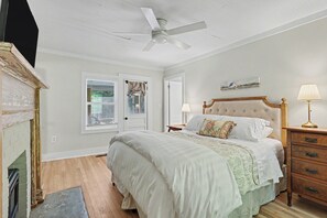 Ein Schlafzimmer mit Bett, Nachttischen, einer Lampe, einem Deckenventilator und einem Bild an der Wand.