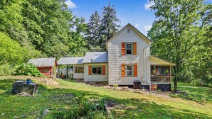A two-story house with a sloped roof, wooden shutters, and a front porch. - Ruby's Coop (Bryson City)