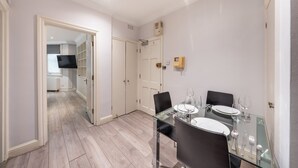 A modern dining area with a glass table, black chairs, and white plates. - Comfort Studio by Harrods (London)