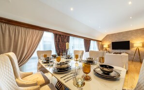 A hotel dining room with a large table set for a meal, comfortable seating, a television, and a lamp. - Spacious Penthouse Near Hyde Park London (London)