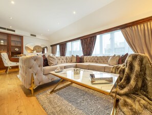A spacious living room with a large sectional sofa, a glass coffee table, and a fur throw. - Spacious Penthouse Near Hyde Park London (London)