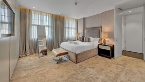 A modern hotel room with a large bed, a bedside table, a mirror, and a window with curtains. - Beautiful Apartment With Lift in Baker St (London)
