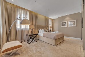 Ein Schlafzimmer mit einem Bett, einem Schreibtisch, einem Stuhl und einem großen Fenster mit Vorhängen.