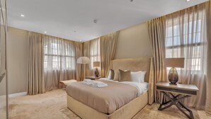 A spacious bedroom with a large bed, two bedside tables with lamps, and a view of the city through sheer curtains. - Beautiful Apartment With Lift in Baker St (London)