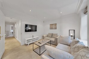 Ein modernes Wohnzimmer mit Flachbildfernseher, einer Couch, einem Couchtisch und einem Fernsehmöbel.