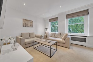 Ein modernes Wohnzimmer mit zwei Sofas, einem Couchtisch, einer Blumenvase und einem Bild an der Wand.