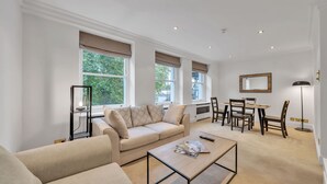 A modern living room with a sofa, coffee table, and dining area. - Charming 2-bedroom Apartment in Knightsbridge (London)