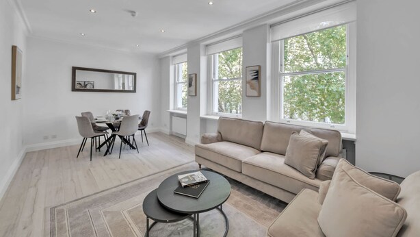 Ein modernes Wohnzimmer mit einer Couch, einem Couchtisch und einem Essbereich mit Stühlen und einem Tisch.