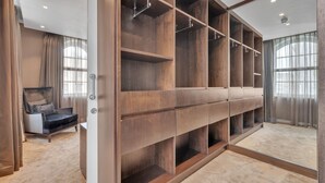 A walk-in closet with multiple shelves and hanging space, a chair, and a large window with curtains. - Elegant Apartment in Marylebone (London)