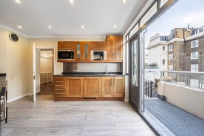Eine moderne Küche mit Holzschränken, Edelstahlgeräten und einem großen Fenster mit Blick auf eine Stadtlandschaft.