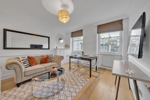 Ein modernes Wohnzimmer mit Sofa, Couchtisch, Esstisch und Fernseher.