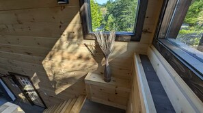 Ein Holzblockhaus-Innenraum mit Fenster, einer Vase mit Zweigen und einer Tür.