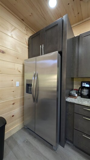 Ein Edelstahl-Kühlschrank in einer Küche mit Holzpaneelen und einer Arbeitsplatte aus Granit.