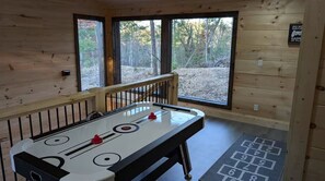 Ein Zimmer mit Shuffleboard-Tisch, einem Fenster mit Blick auf Bäume und einem Bitte-nicht-stören-Schild.
