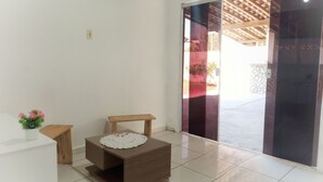 A room with a small wooden table, a matching bench, a decorative doily, and a view through a glass door to an outdoor area with a wooden ceiling structure.